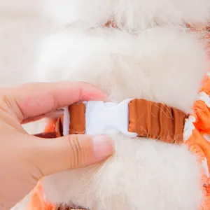 Detail view of durable white plastic buckle on orange dog dustproof outdoor suit pants