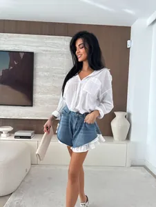 Dettaglio ravvicinato di pantaloncini di jeans a vita alta con eleganti volant bianchi
