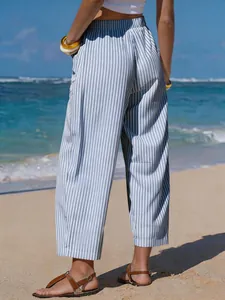 Back view of women's blue and white striped faux linen cropped pants on a sunny beach.