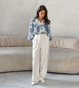 Full view of blue and white printed stand collar blouse with cream wide leg trousers.