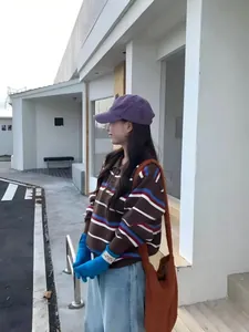 Détail d'un pull polo rayé pour femme dans un cadre extérieur minimaliste moderne.