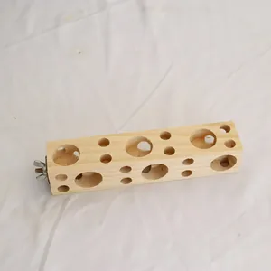 Nahaufnahme eines Papageienspielzeugs aus Holz mit Löchern und einer Befestigungsschraube