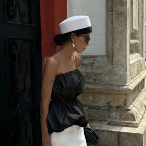 Elegant black strapless peplum top for women styled with a white pillbox hat and sunglasses