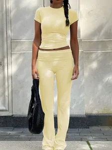 Detailed full-body shot of a yellow women's two-piece sportswear set with low-waist flared pants