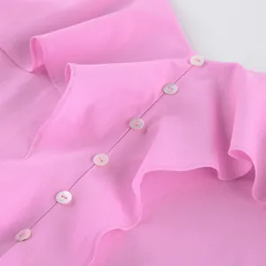 Détail d'un haut en coton rose avec des volants élégants et des boutons blancs à l'avant.
