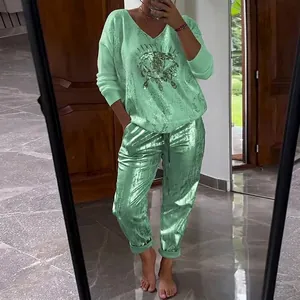 Woman wearing a stylish shiny light green 2-piece lounge set with sequined eye graphic