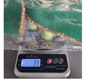 Close-up of green Christmas bow with gold glitter edge being weighed on a digital scale
