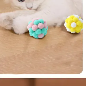 Detail of soft macaron plush balls for interactive cat play on wood floor.