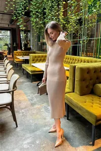 Elegant beige ribbed knit long sleeve bodycon midi sweater dress in a cafe setting