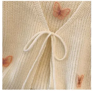 Detailed close-up showing pink butterfly embroidery and front tie on cream crochet cardigan
