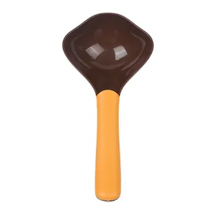 Detalle superior de una pala de comida para mascotas bicolor con mango de color naranja