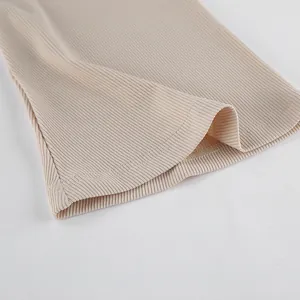 Détail du tissu en maille côtelée abricot montrant les coutures fines et la texture
