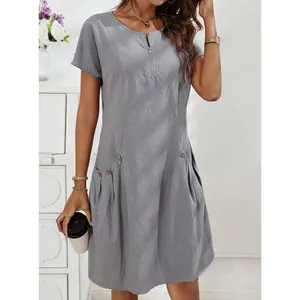 Detail view of cotton linen dress featuring zipper neckline and decorative pocket buttons