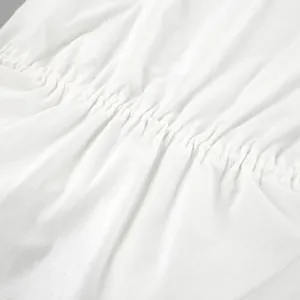 Detailed close-up view of smocked elastic waist on a white cotton linen summer outfit.