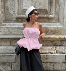 Stylish model showcasing a light pink strapless peplum top in an outdoor urban setting