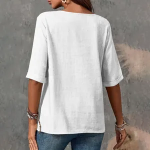 Vista posteriore dettagliata del top casual in cotone e lino bianco con polsini risvoltati.