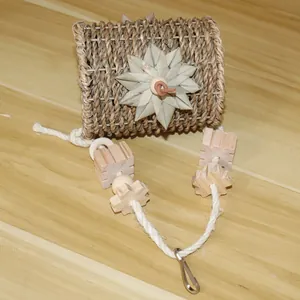 Detail view of woven grass bird nest toy with hanging wooden blocks and metal clip