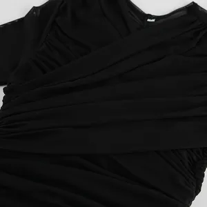 Detailed close-up of a black V-neck top featuring elegant ruched fabric and sheer mesh sleeves