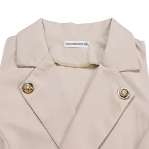 Detail view of a beige jumpsuit featuring a notched lapel and ornate gold lion-head buttons.
