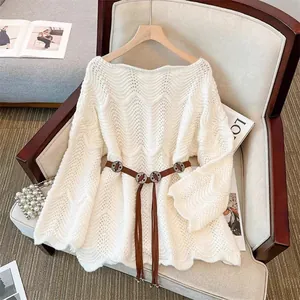 Detailansicht des weißen Strickpullovers mit Wellenmuster und braunem Fransen-Gürtel.
