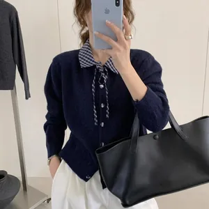 Détail d'un cardigan chic en maille bleu marine avec un col chemise à carreaux noué