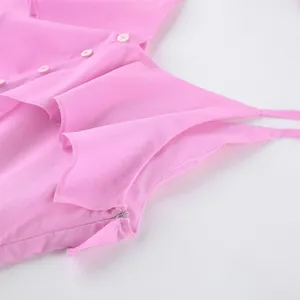 Détail en gros plan du haut rose en coton avec volants et fermetures à boutons délicates.