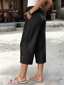 Seitenansicht der schwarzen Tencel-Denim-Caprihose mit Zierknöpfen am Saum