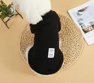 Detailansicht schwarzer gestrickter Hundepullover mit Lucky Bear Patch auf Strohmatte.