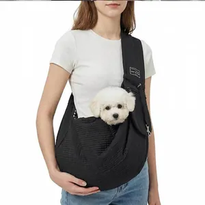 Black quilted pet sling carrier for small dogs shown in use with a small white puppy