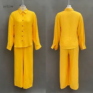 Detail of yellow two-piece set featuring long-sleeve button-down shirt and wide-leg pants