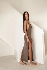 Side view of a sexy brown knitted maxi dress featuring a high slit and backless design