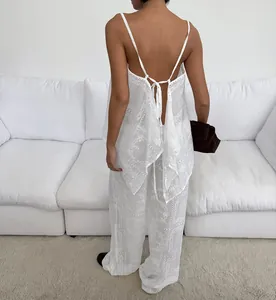 Vue détaillée d'un ensemble deux pièces blanc brodé avec caraco en dentelle et pantalon.