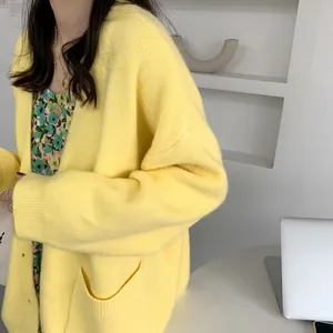 Close-up view of a loose yellow knitted cardigan featuring side pockets and soft texture.
