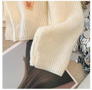 Detailed macro view of cream knitted cardigan texture with orange butterfly patch embroidery