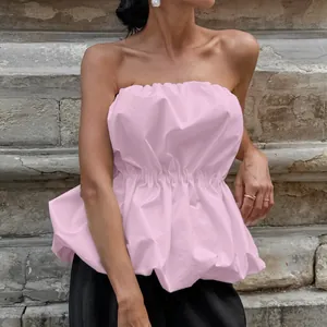 Detailed view of a pink strapless top with a smocked waist and puffy peplum design.