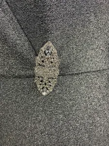 Detailansicht der Kristallbrosche auf glänzendem silbernen V-Ausschnitt Kleid