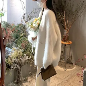 Elegant soft white fuzzy oversized cardigan sweater for women in a warm aesthetic setting