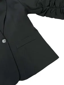 Gros plan d'un blazer noir pour femme avec manches froncées et détails de poche