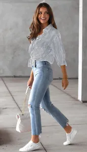 Frau trägt ein gestreiftes Hemd, das für einen modischen Look in der Taille geknotet ist