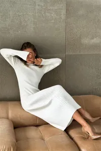 Elegant white long sleeve ribbed knit maxi dress shown in a lifestyle setting.