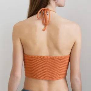 Detailed back view of orange knitted halter neck crop top with tie straps.