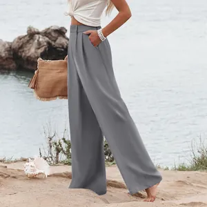 Eleganti pantaloni casual grigi a vita alta e gamba larga per donna in un ambiente balneare