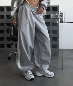 Detail of loose grey and white color-blocking tracksuit pants on a model in a studio