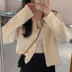 Detailopname van een vintage crème gebreid vest met parelknopen en textuurpatroon