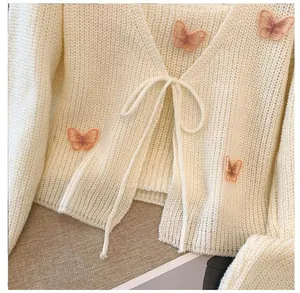 Close-up of French-style knit cardigan with 3D butterfly patches and tie-front detail.