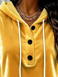 Close-up detail of yellow velvet hoodie with black buttons and white drawstrings