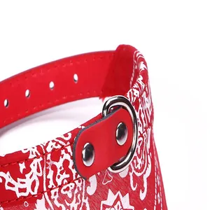 Macro detail of a red pet bandana collar with white paisley pattern and metal D-ring