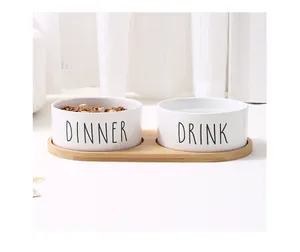 Nahaufnahme minimalistischer Keramik-Haustiernapf mit 'DINNER' und 'DRINK' auf Bambustablett