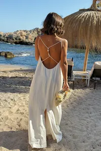Back view of a white backless holiday maxi dress with thin straps on a sunny beach