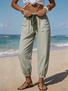 Close-up of olive green striped linen-like joggers with drawstring waist at the beach